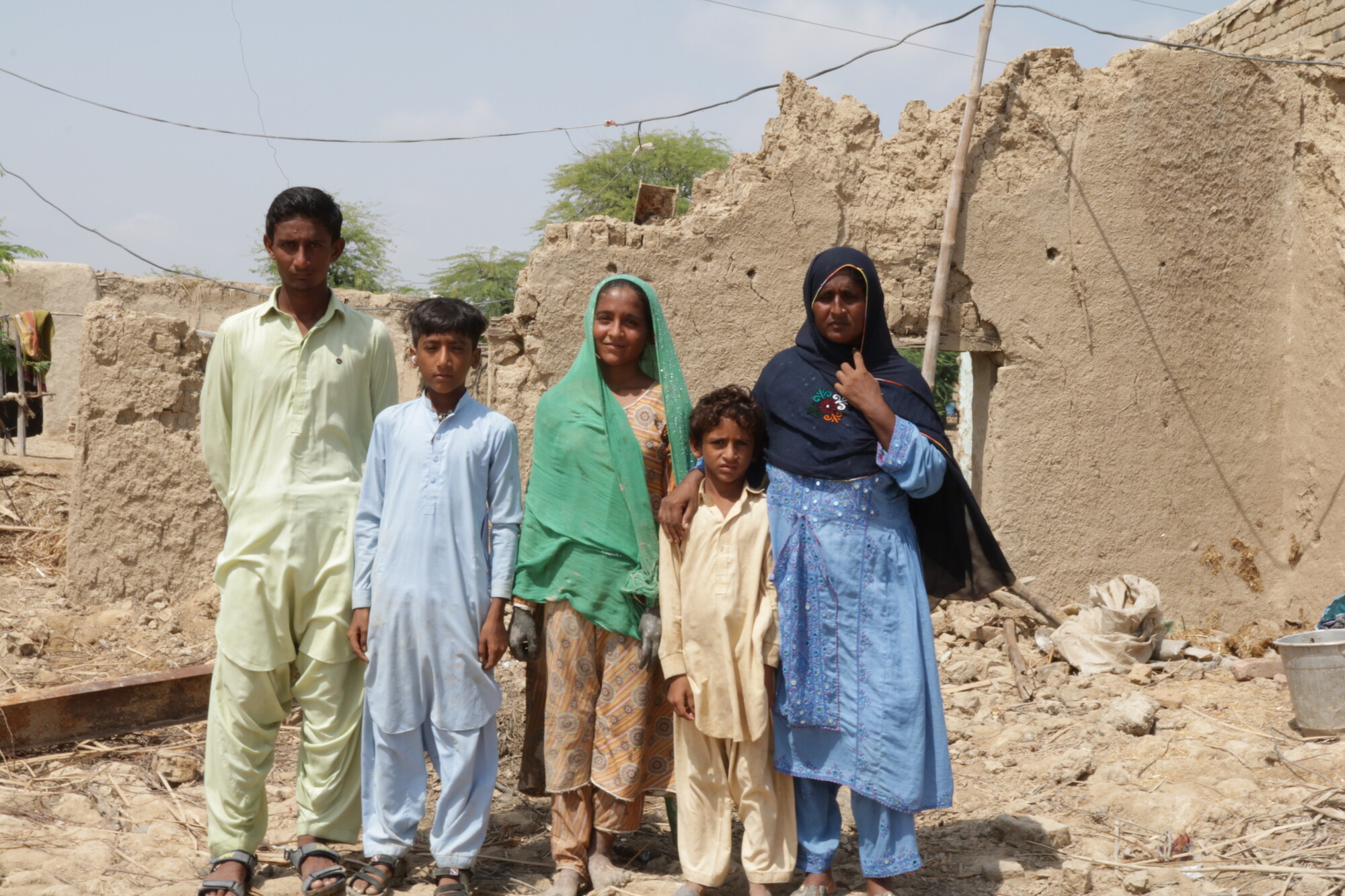 Bano with her children in front of their house which was destroyed during the floods